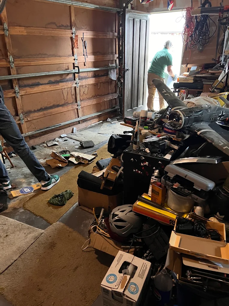 A 220-JUNK crew member clearing a packed garage